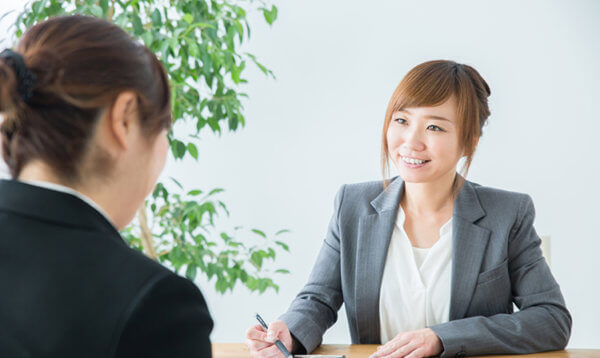 ジャケットを着ている女性が書類を使って説明をしている