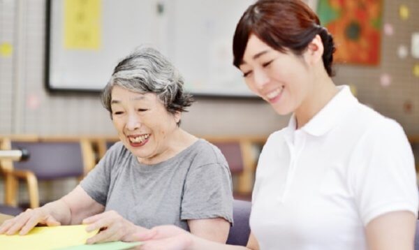 女性の介護士がご老人と本を見ている写真