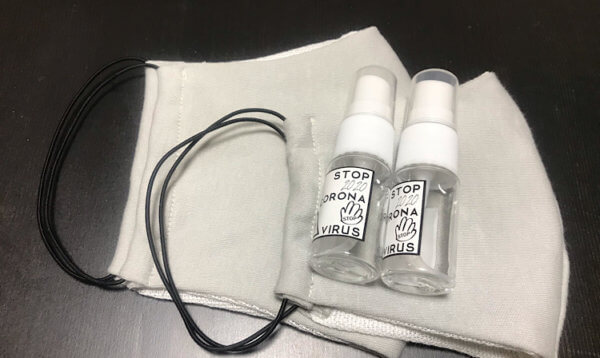 グレーの手作りマスクとアルコールスプレーの写真