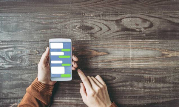 茶色の服を着た人がスマートフォンでメッセージを確認している写真